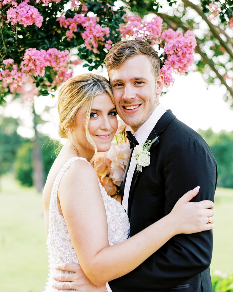 Bride and groom pose in front of a crape myrtle tree