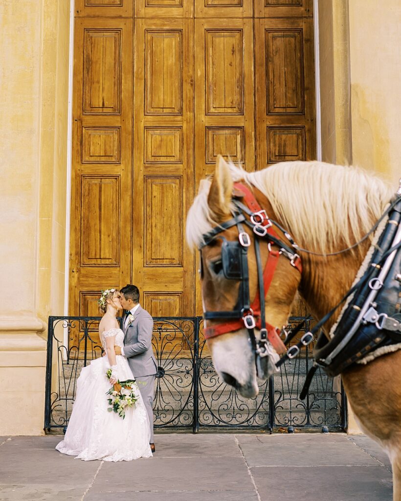 A horse walks by as the couple poses for a picture
