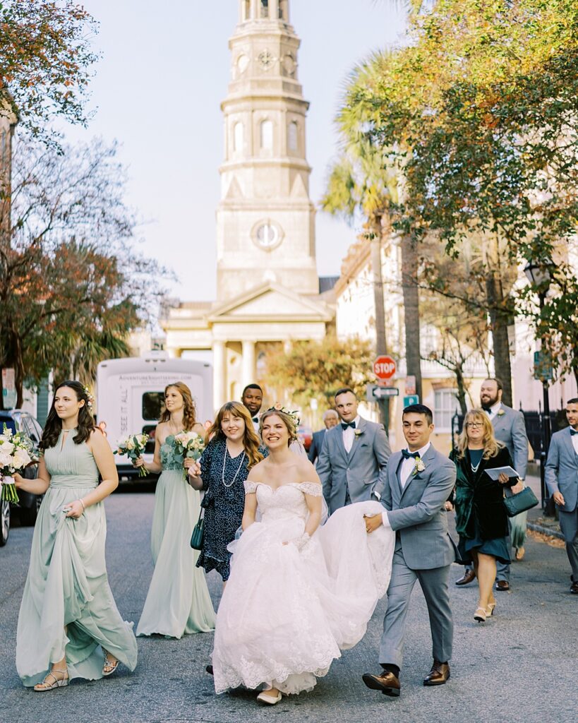 The bride, groom, and bridal party walking in front of St Philip's Church