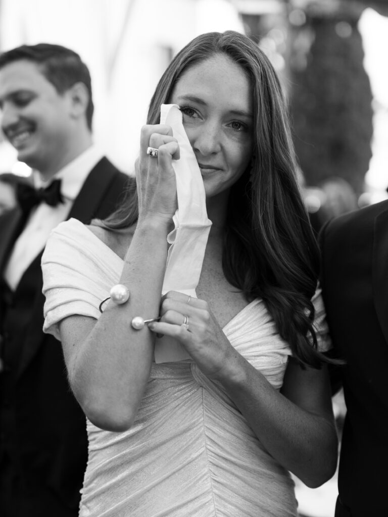 A wedding guest wipes her tears