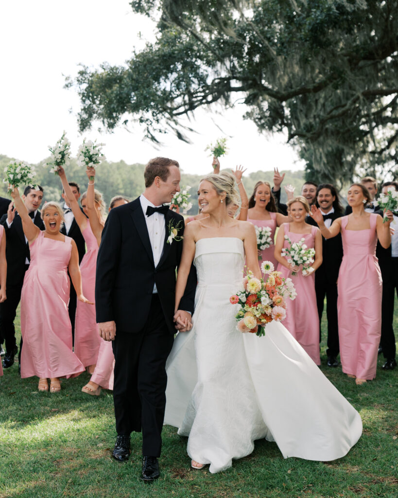 bride and groom walking with wedding party behind them